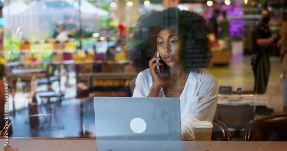 Confident multi-ethnic woman, manager or sales representative making call on smartphone, drinking takeaway hot drink from paper cup, working on laptop computer indoors. Working from coffee shop Confident multi-ethnic woman, manager or sales representative making call on smartphone, drinking takeaway hot drink from paper cup, working on laptop computer indoors. Working from coffee shop