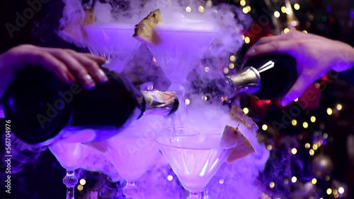 champagne is poured into a pyramid of glasses with pineapple pieces, bubbles and smoke at a christmas party photo