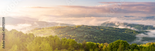 panorama of mountains in fog at sunrise. A foggy landscape Panorama. A fantastic dreamy sunrise on the mountains with a view of the misty valley below. Misty clouds over the forest. 