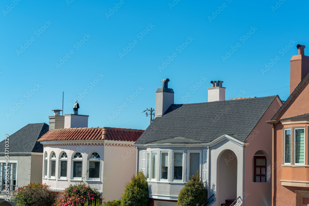 Upper house exteriors with visible windows and chimney vents or pipes with stucco facades in middle class suburbs