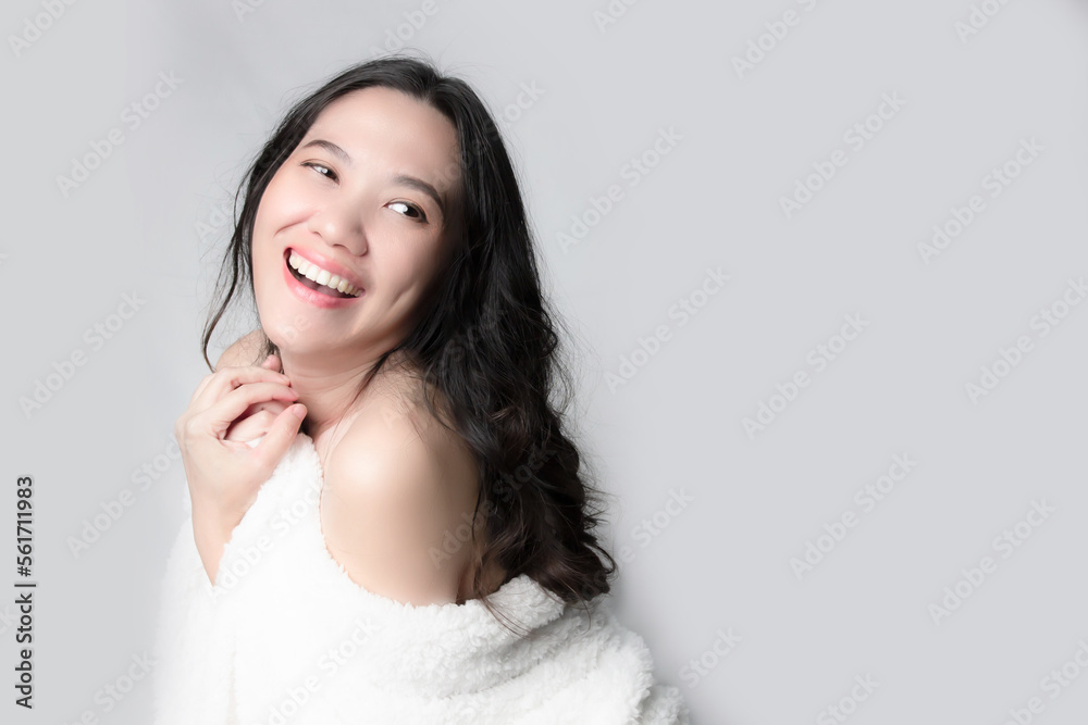 Asian beautiful woman cover with white fur blanket and show skin is looking away with smile and happiness. Mental wellness or skin care and beauty concept Asian beautiful woman cover with white fur blanket and show skin is looking away with smile and happiness. Mental wellness or skin care and beauty concept