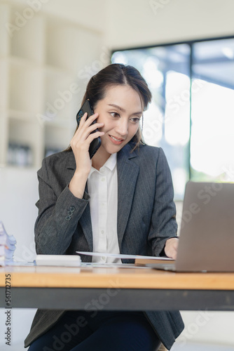 Asian businesswoman working with various electronic internet devices, independent woman having tablet and laptop with chart, multitasking theme, financial accounting concept. vertical image