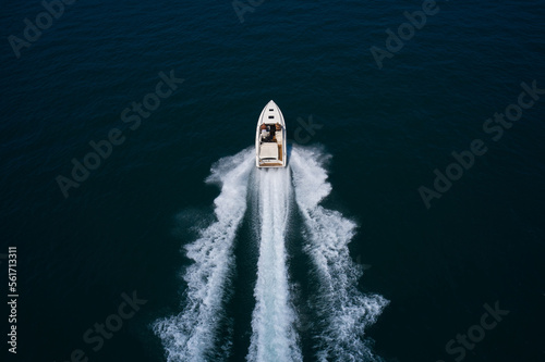 Big speedy white boat fast movement on dark water top view.