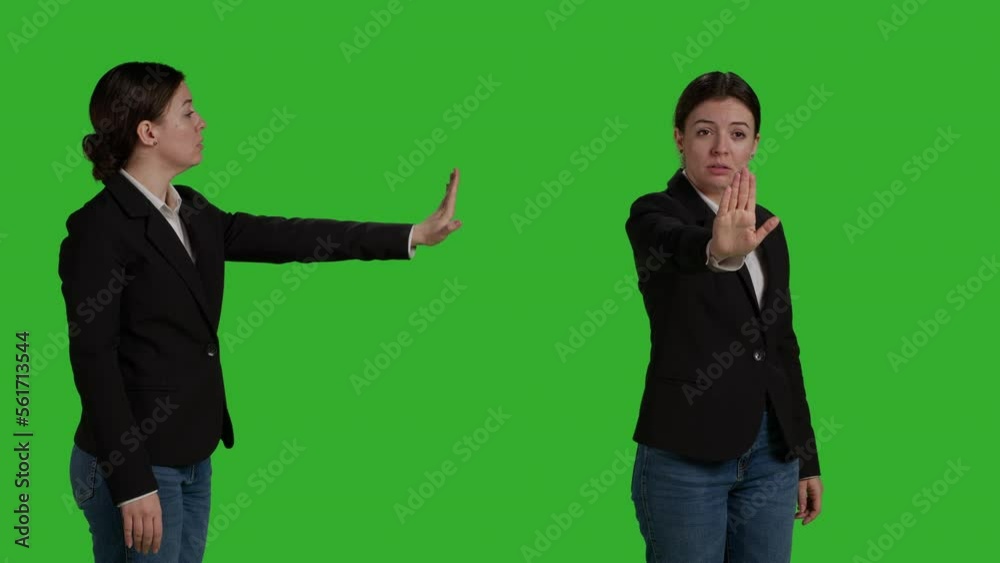 Close up of young manager showing stop talking sign with palm, expressing negative gesture and denial. Female worker in office suit doing rejection and refusal symbol over greenscreen backdrop. Close up of young manager showing stop talking sign with palm, expressing negative gesture and denial. Female worker in office suit doing rejection and refusal symbol over greenscreen backdrop.