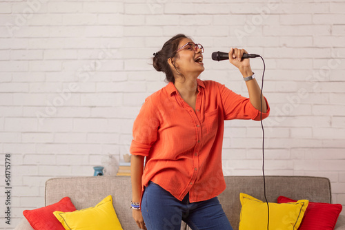 Obraz na plátně Portrait of a young woman singing in living room at home