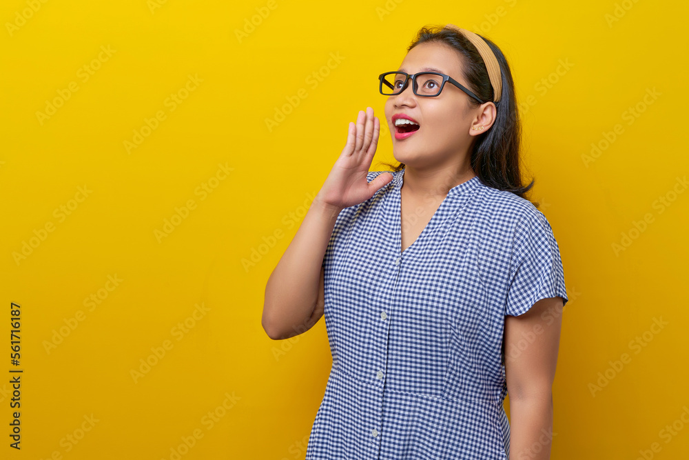 Beautiful surprised young Asian woman 30s wearing a dress checkered with glasses looking away with an open mouth isolated on yellow background. people lifestyle concept Beautiful surprised young Asian woman 30s wearing a dress checkered with glasses looking away with an open mouth isolated on yellow background. people lifestyle concept