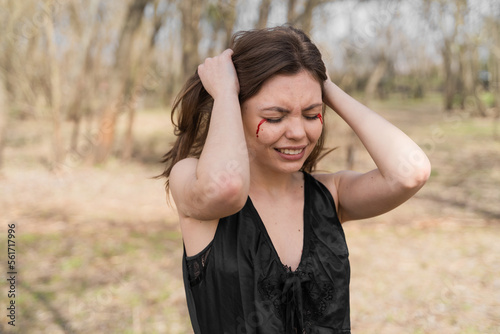 Crying Ukrainian woman with a bloody tears. Young caucasian woman emotionally pulls out hair on the head.