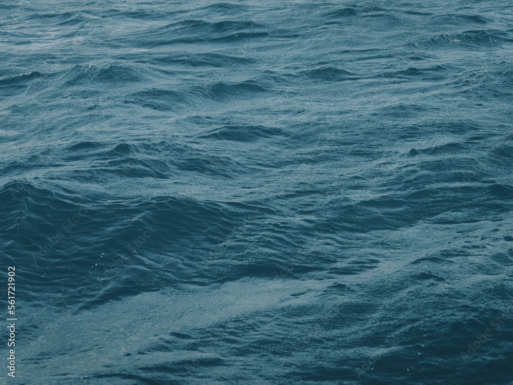 Fototapeta premium Dark blue-green color of water surface with waves in middle of endless deep sea. Endless wavy expanse of blue sea water. Dark blue waves in deep ocean. Raging aquamarine waves on surface of the water.