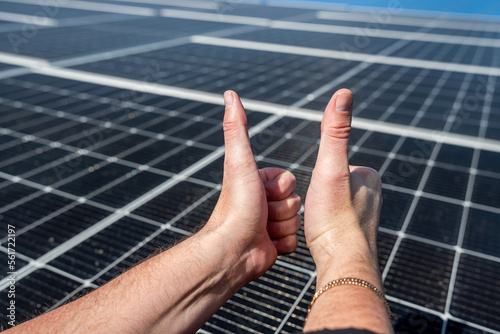 solar panel on the roof produces electricity on the background of a hand with a finger up.