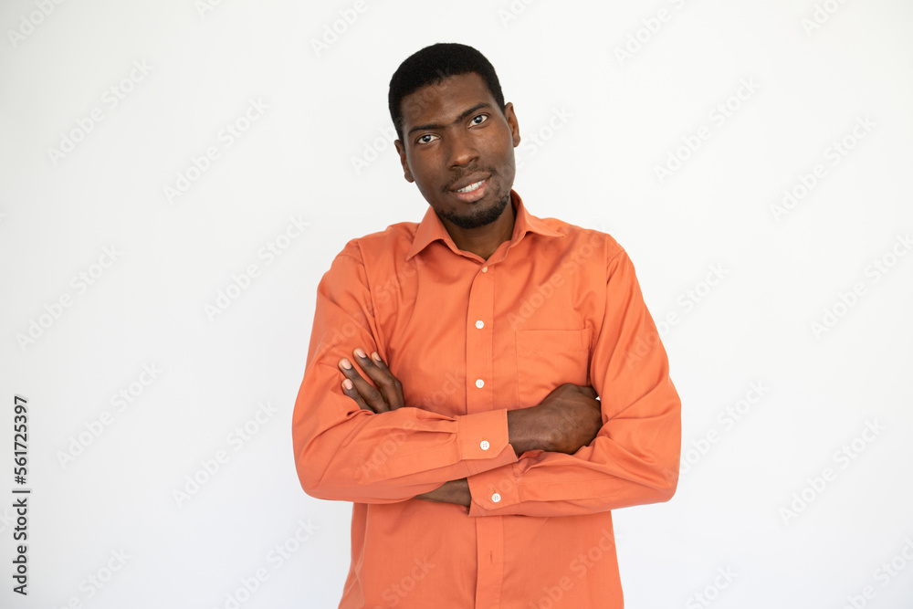 Portrait of happy young man posing with folded arms over white background. African American guy wearing orange shirt looking at camera and smiling. Confidence concept Portrait of happy young man posing with folded arms over white background. African American guy wearing orange shirt looking at camera and smiling. Confidence concept