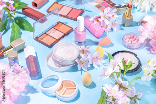Spring make up set on light blue background. Different make-up professional cosmetics, beauty accessories flat lay with spring blossom flowers top view copy space