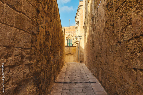 Ancient narrow medieval cobblestone street in town Mdina, Malta with nobody in sunny day. Travel destination