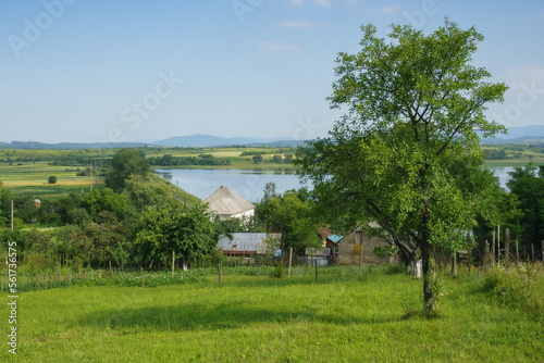 countryside lake in summer. mountainous rural area with village in the valley