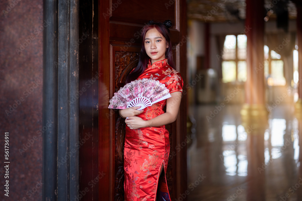 portrait of beautiful asian woman in traditional Chinese dress holding fan in Chinese shrine in Chinese new year festival celebration