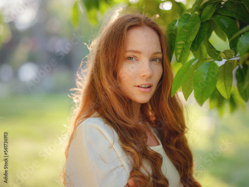 Beauty Woman Face With Healthy Skin And Green Plant at sunset time outdoor. Healthy lifestyle, beauty, natural concept. Melancholic beautiful portrait photo
