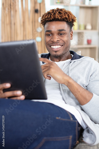 happy man using tablet on sofa at his modern home