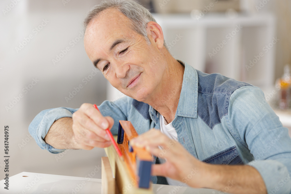 senior male carpenter using level on wood board senior male carpenter using level on wood board
