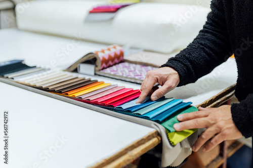 Hands of craftsman choosing fabric color in workshop photo