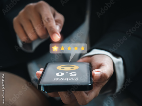Customer review, satisfaction, feedback, survey concepts. The User giving 5 stars point rating with smile face icon to service experience, business ranking on online application by smart mobile phone.