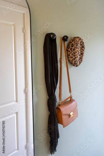 iapparral hanging up in the entrance to an apartment house ladies leather bag scarf and beret hat