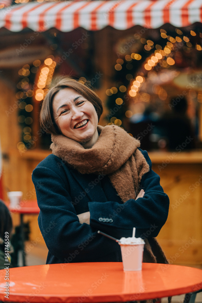 Happy mature woman with arms crossed sitting at sidewalk cafe Happy mature woman with arms crossed sitting at sidewalk cafe