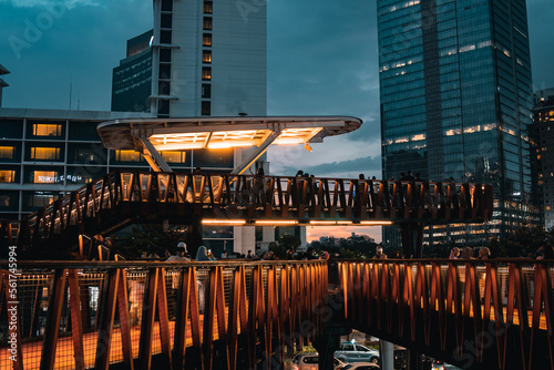 A breath taking view of a ship-shaped pedestrian bridge called "Pinisi" with tall buildings and twilight skies in the background in Karet, Sudirman area.