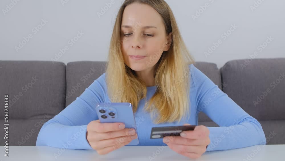 Cheerful customer paying online with a credit card. Adult white woman making an online purchase in a internet store with smart phone app and plastic bank card Cheerful customer paying online with a credit card. Adult white woman making an online purchase in a internet store with smart phone app and plastic bank card