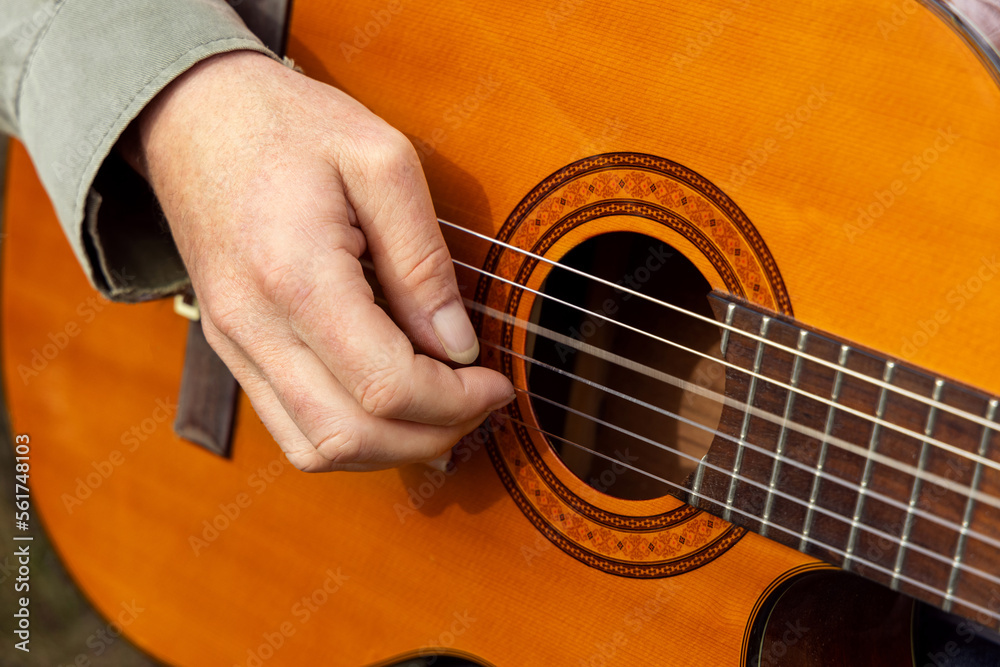 Fototapeta premium Male hands playing acoustic guitar, close up. Teacher is giving guitar lesson