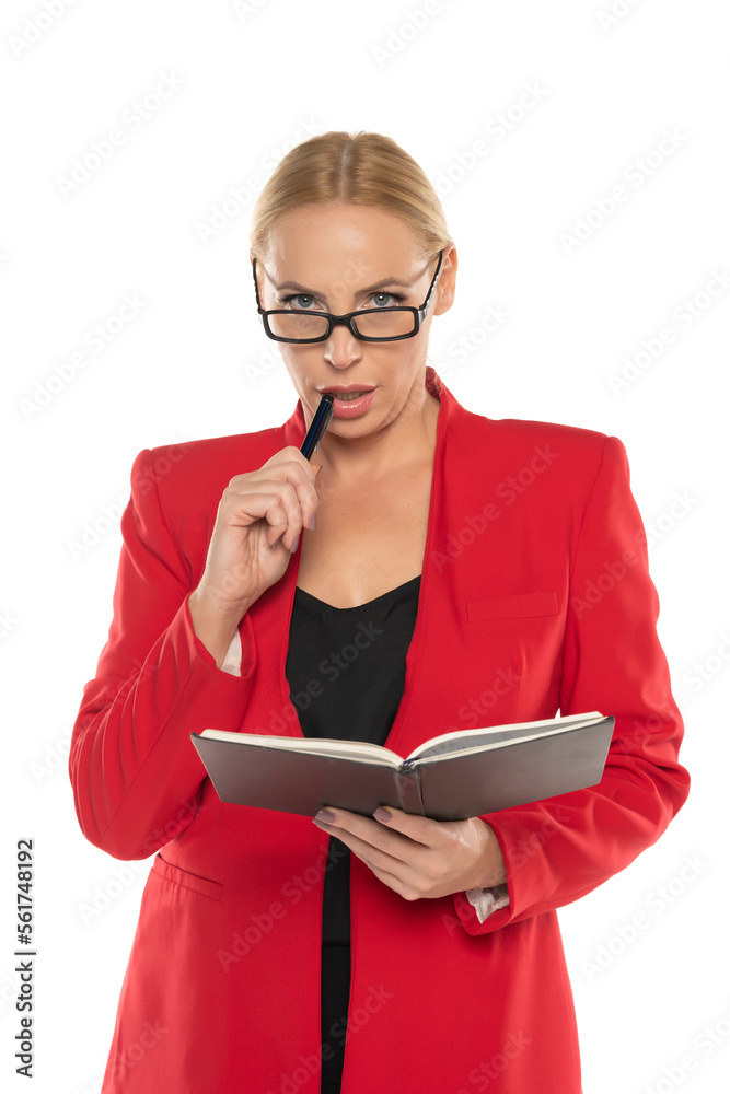 Middle aged senior business woman in red jacket with notebook and pen on white \background Middle aged senior business woman in red jacket with notebook and pen on white \background