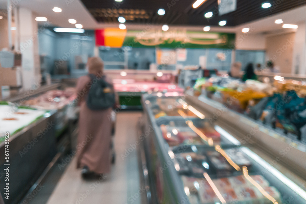 Blurred or defocused supermarket or grocery store with some customers shopping.