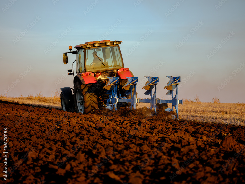 Fototapeta premium Farmer in tractor cultivating stubble field for crop planting and cultivation
