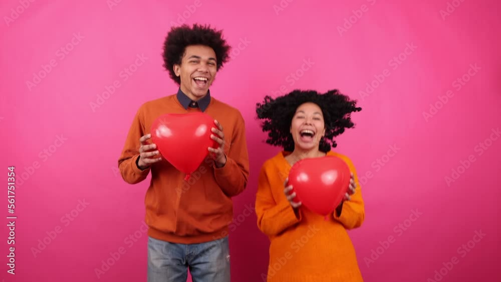 Young people of African American ethnicity holding red, heart-shaped balloons and jumping. Close-up shot of cheerful married couple. High quality 4k footage Young people of African American ethnicity holding red, heart-shaped balloons and jumping. Close-up shot of cheerful married couple. High quality 4k footage