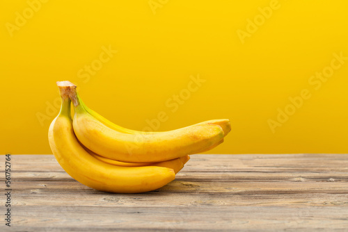 bunch of bananas on  wooden table on yellow background