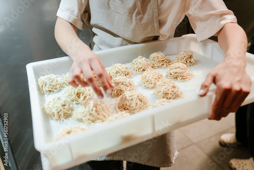 Young woman putting food in refrigerator while working in kitchen photo