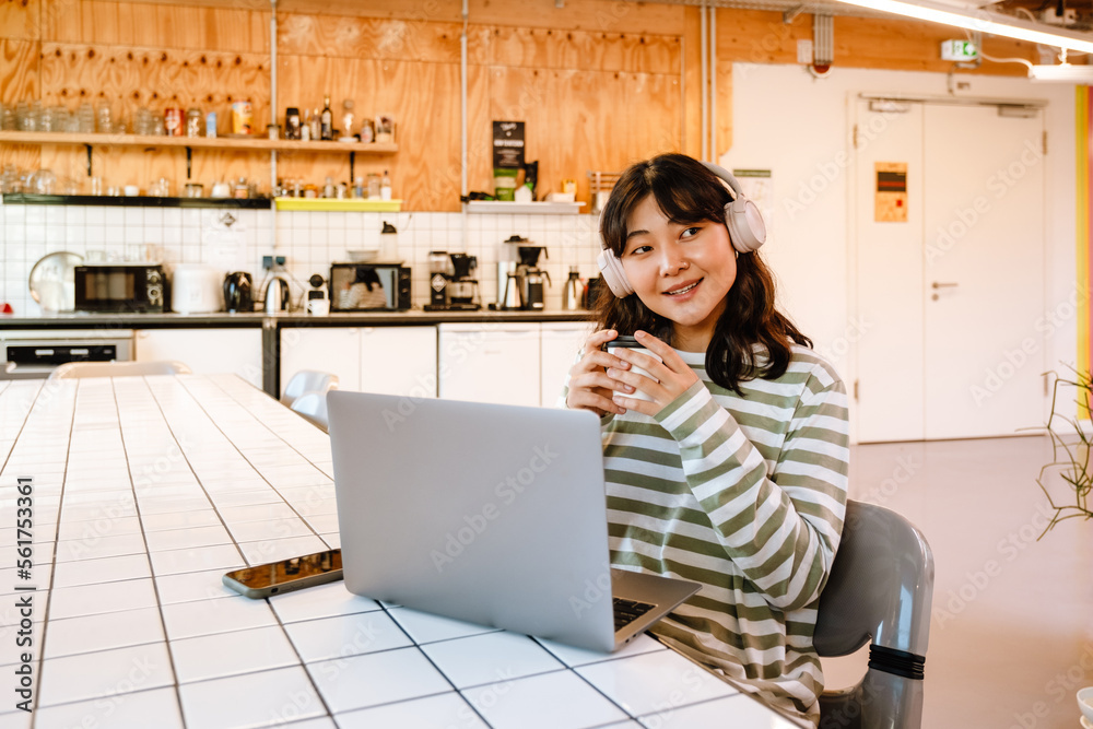 Young asian woman using laptop and headphones in cafe Young asian woman using laptop and headphones in cafe
