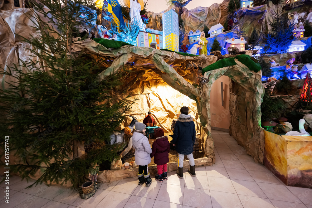 Back of three children looking in Christmas nativity crib scene in church.