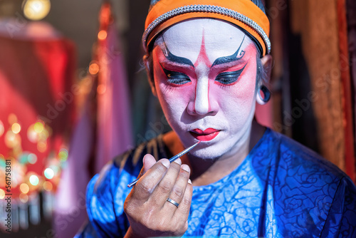 Chinese opera actor cosmetic make up painting face face before perform at back stage of theater photo