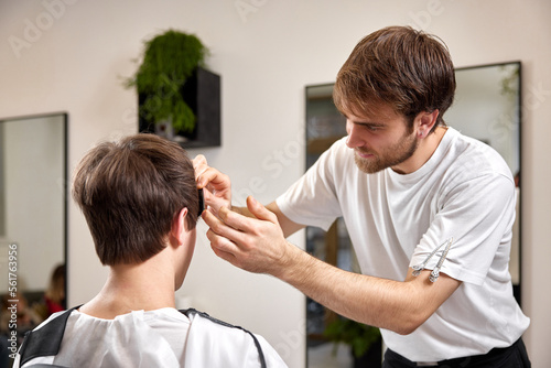 caucasian man getting haircut by professional male hairstylist