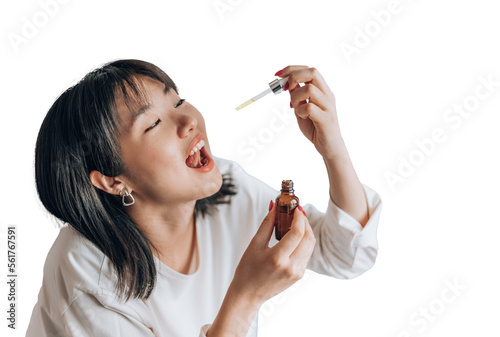 Asian woman dripping cbd oil into her mouth. Close up asian women taking CBD Oil for sleep. Medical cannabis. Vitamins and supplements photo