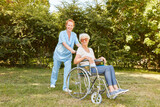 Altenpflegerin schiebt behinderte Seniorin im Rollstuhl