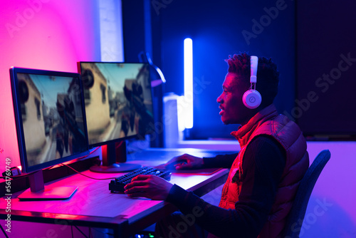 Young African man playing video game on computer. Streamer guy sitting at home and plays another match.