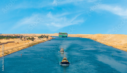 Foto Large container ship, accompanied by tugboat, passing through the Suez Canal in Egypt