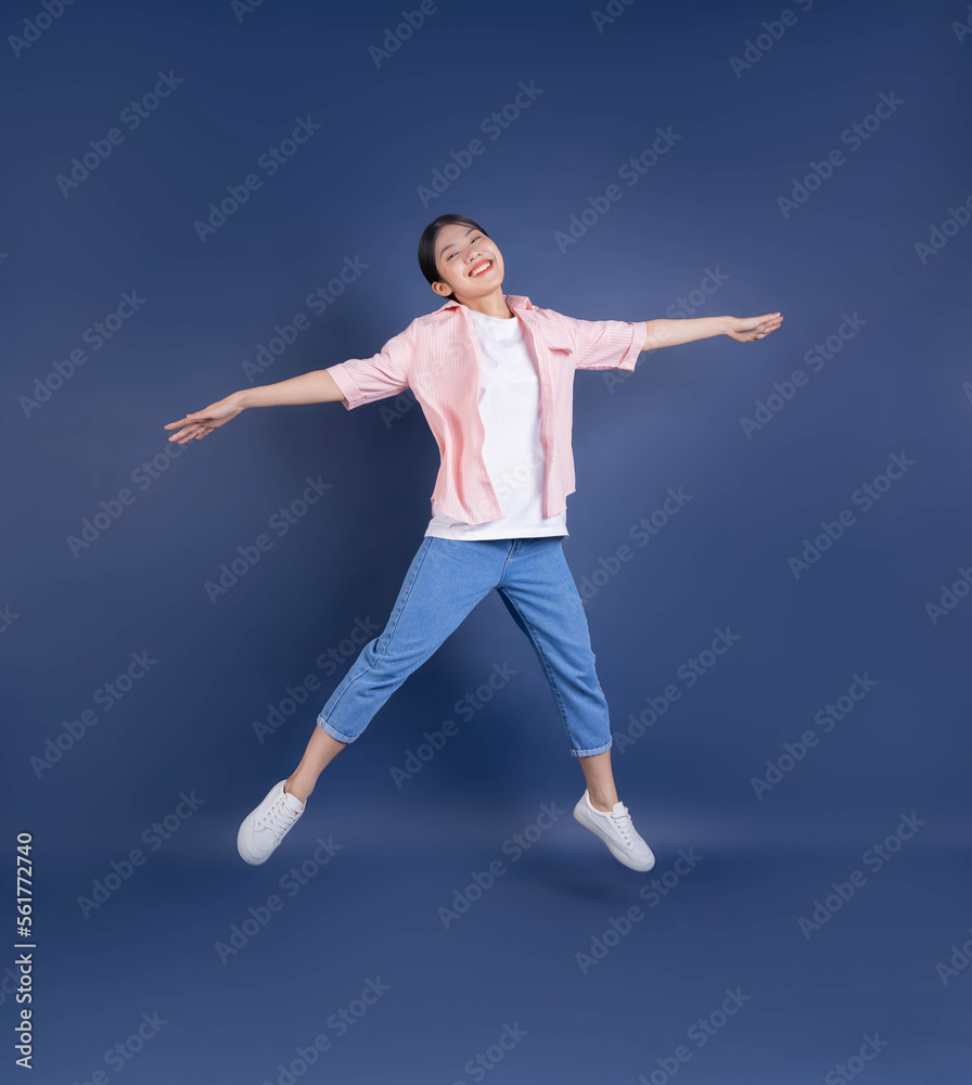 Full length image of young Asian woman standing on background