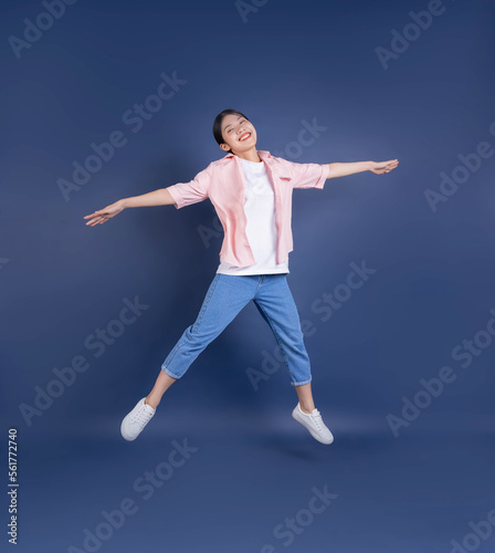Full length image of young Asian woman standing on background