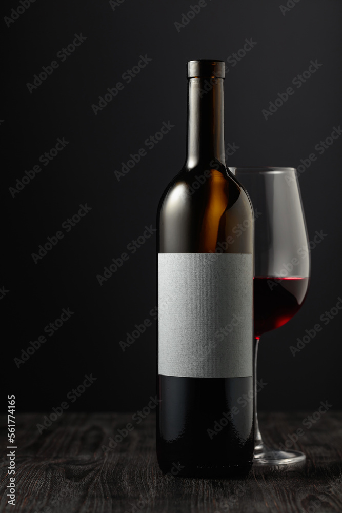 Fototapeta premium Bottle and glass of red wine on a black table.