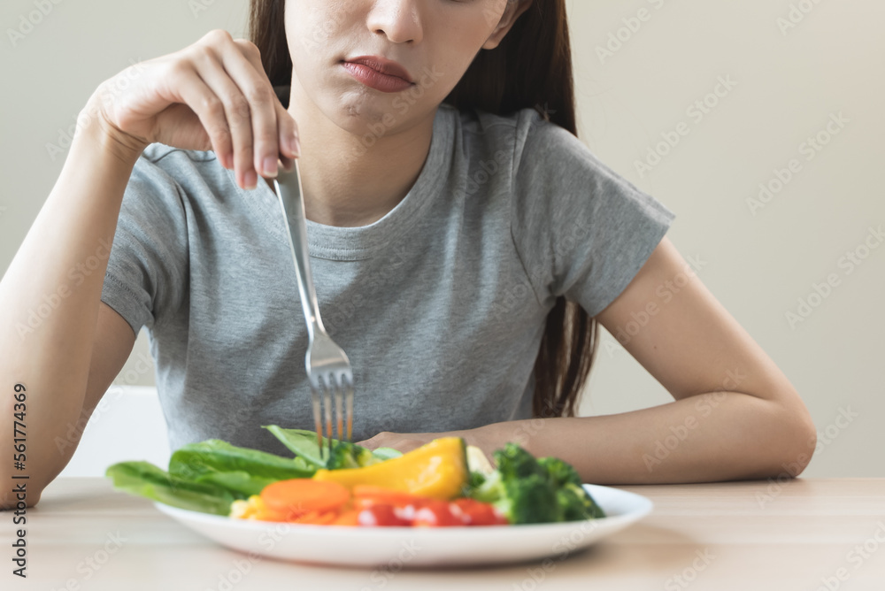 unhappy asian women is on dieting time looking at broccoli on the fork. girl do not want to eat vegetables and dislike taste unhappy asian women is on dieting time looking at broccoli on the fork. girl do not want to eat vegetables and dislike taste