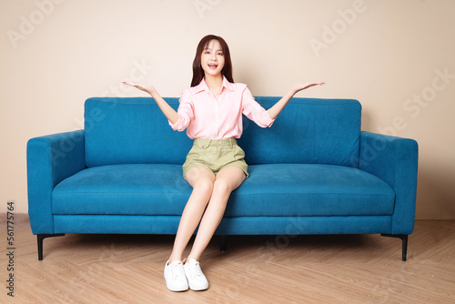 Image of young Asian woman sitting on sofa