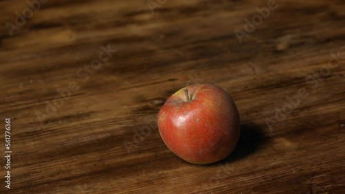 Three Boskoop apples are taken by a man's hand from a wooden table with brown structure in slow motion. photo