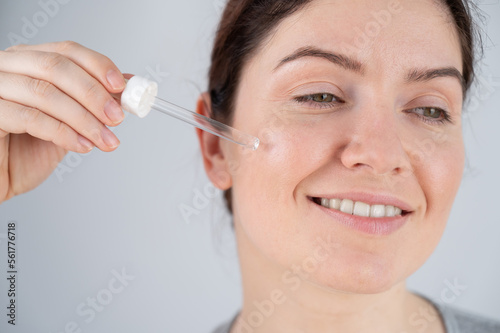 Caucasian woman uses blue anti-wrinkle face serum.