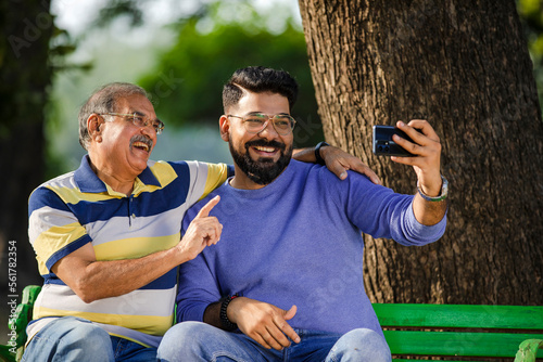 Young man taking selfie with his father at park.